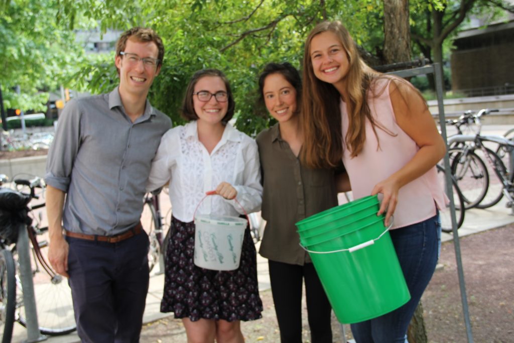 Green Fund Program Manager Ian Aley, and students Jackie Millonzi, Lauren Lucas, and Katie Piel stand with one of the new green compost buckets purchased through the Green Fund.
