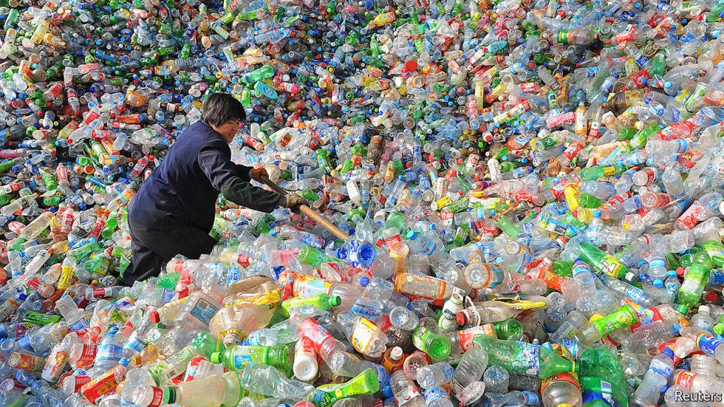 A worker in a pile of plastic bottles. Image courtesy the The Economist. 