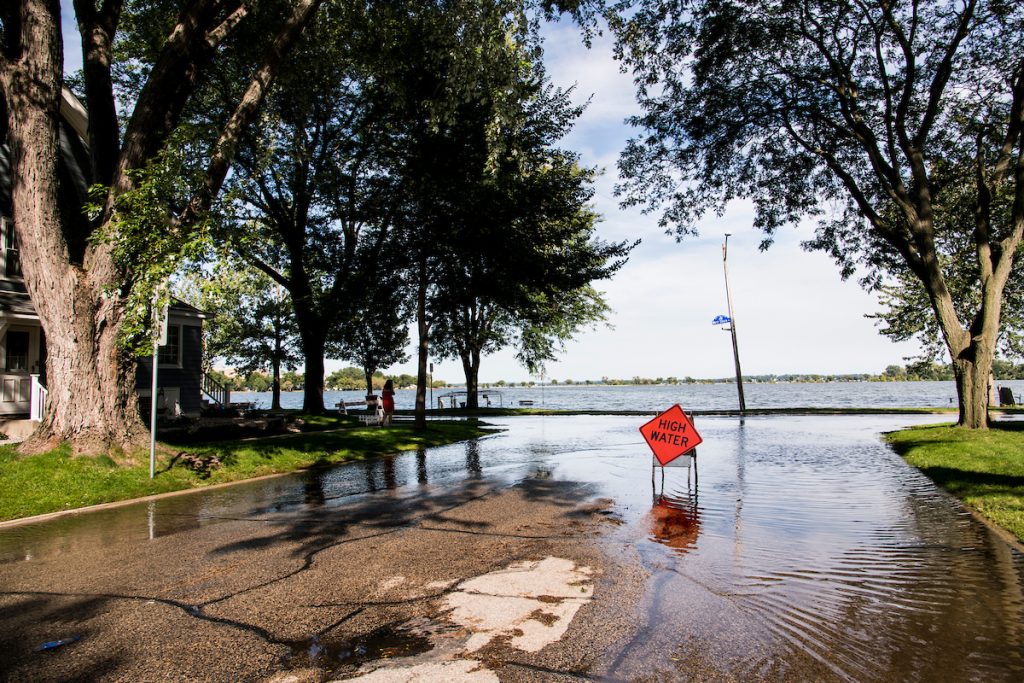 A road hazard sign warns of high-standing water flooding West Shore Drive along Monona Bay in Madison, Wis., during summer on Sept. 6, 2018. Area lake levels continue to rise after a record-breaking storm on Aug. 20 dumped more than 10-inches of rain on parts of Dane County, also flooding areas of the University of Wisconsin-Madison campus lakeshore. (Photo by Jeff Miller / UW-Madison).