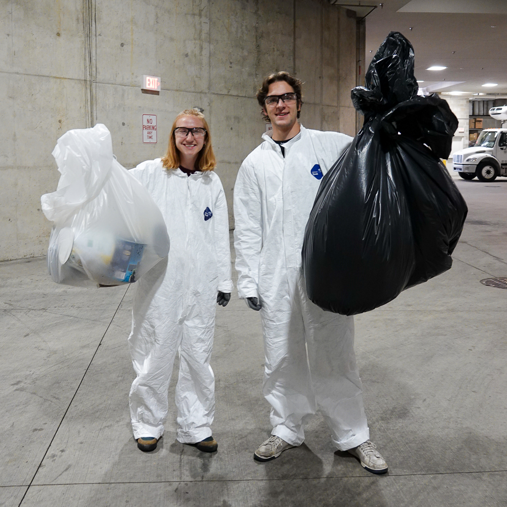 Office of Sustainability student interns Natalie Brunner and Jackson Webster hoist trash and recycling bags during a trash audit. 
