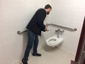 Dan Mrotek checks the flow rate of toilet during the research stage of the Green Fund project. Photo by Ian Aley.