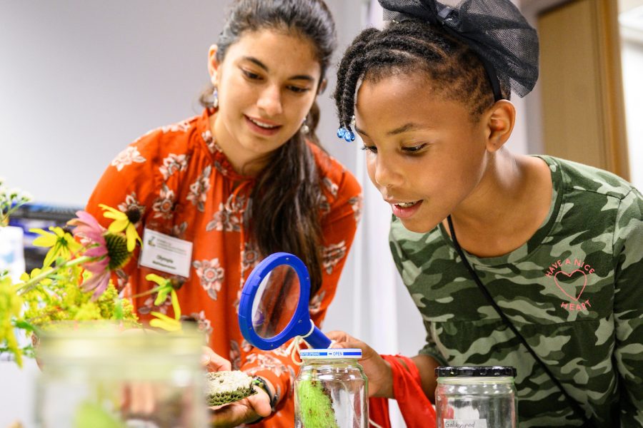 Amelia Pearson (right) listens to Olympia Mathiaparanam, research specialist at the Wisconsin Center for Education Research, at a Lakeshore Nature Preserve education table during a UW-Madison South Madison Community Partnership event held in Villager Mall on Park Street on Sept. 12, 2019.