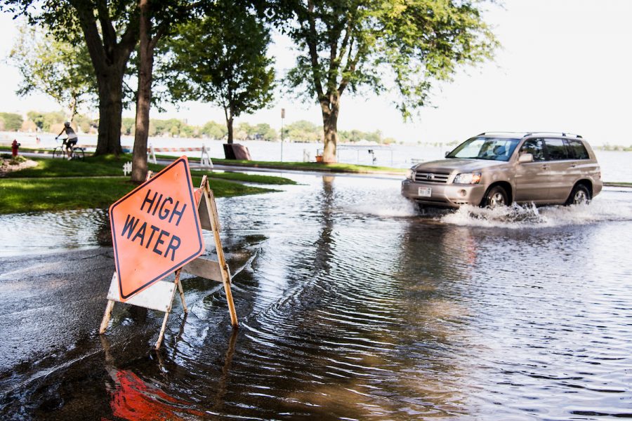 A road hazard sign warns of high-standing water flooding West Shore Drive along Monona Bay in Madison, Wis., during summer on Sept. 6, 2018.