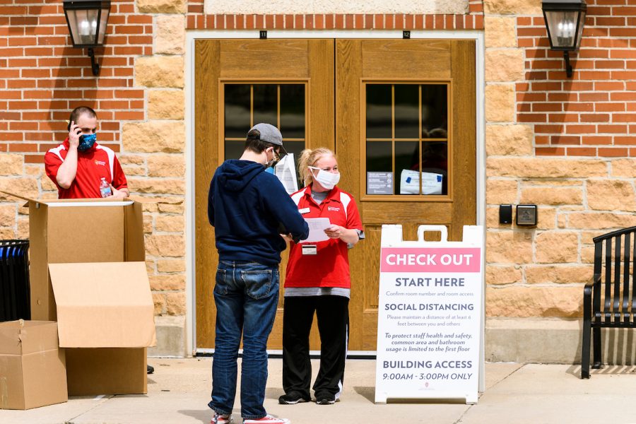 On May 2, 2020, UW Housing staff Trevor Potter, left, and Polly Bartelt check in a student at Tripp-Adams Residence Hall as some student residents return to campus to gather their belongings from UW Housing facilities at the University of Wisconsin-Madison. The staggered move-out process, occurring April 27-May 7, requires people to practice social distancing and safety protocols. Many student residents left campus for UW-Madison Spring Break in mid-March thinking the UW-Madison campus would only be temporarily closed in response to health concerns of the global coronavirus (COVID-19) pandemic. (Photo by Jeff Miller / UW-Madison)