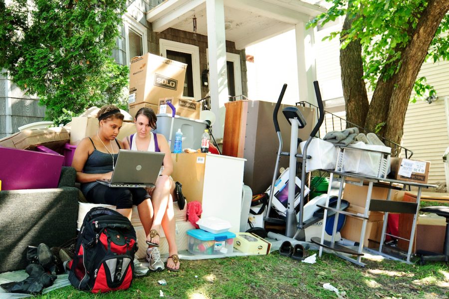 On Aug. 14, 2011, University of Wisconsin-Madison undergraduates Lisa Diaz (left) and Megan Tyson (right) are surrounded by their possessions on the lawn of their campus-area rental house during the annual Madison move-out/move-in weekend. With housing leases ending on Aug. 14 and a new leases taking effect on Aug. 15, landlords have a window of time to clean, paint and make necessary repairs. In the meantime, tenants must find temporary shelter for themselves and their belongings. (Photo by Bryce Richter / UW-Madison)