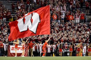 A cheerleader with the UW Spirit Squad runs a large W flag across the field during a season-opening, night football game between the Wisconsin Badgers and the Western Kentucky Hilltoppers at Camp Randall Stadium at the University of Wisconsin-Madison on Aug. 31, 2018. The Badgers won, 34-3. (Photo by Jeff Miller / UW-Madison)