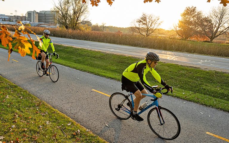 Pedestrians and cyclist travel among the colors of the fall leaves on the Howard Temin Lakeshore Path at the University of Wisconsin-Madison during autumn on November 8, 2021.