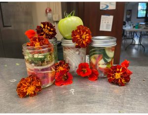 Flowers and jarred pickled vegetables on a table