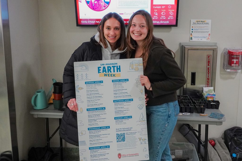 Two interns posing with a poster in Chadbourne Hall.